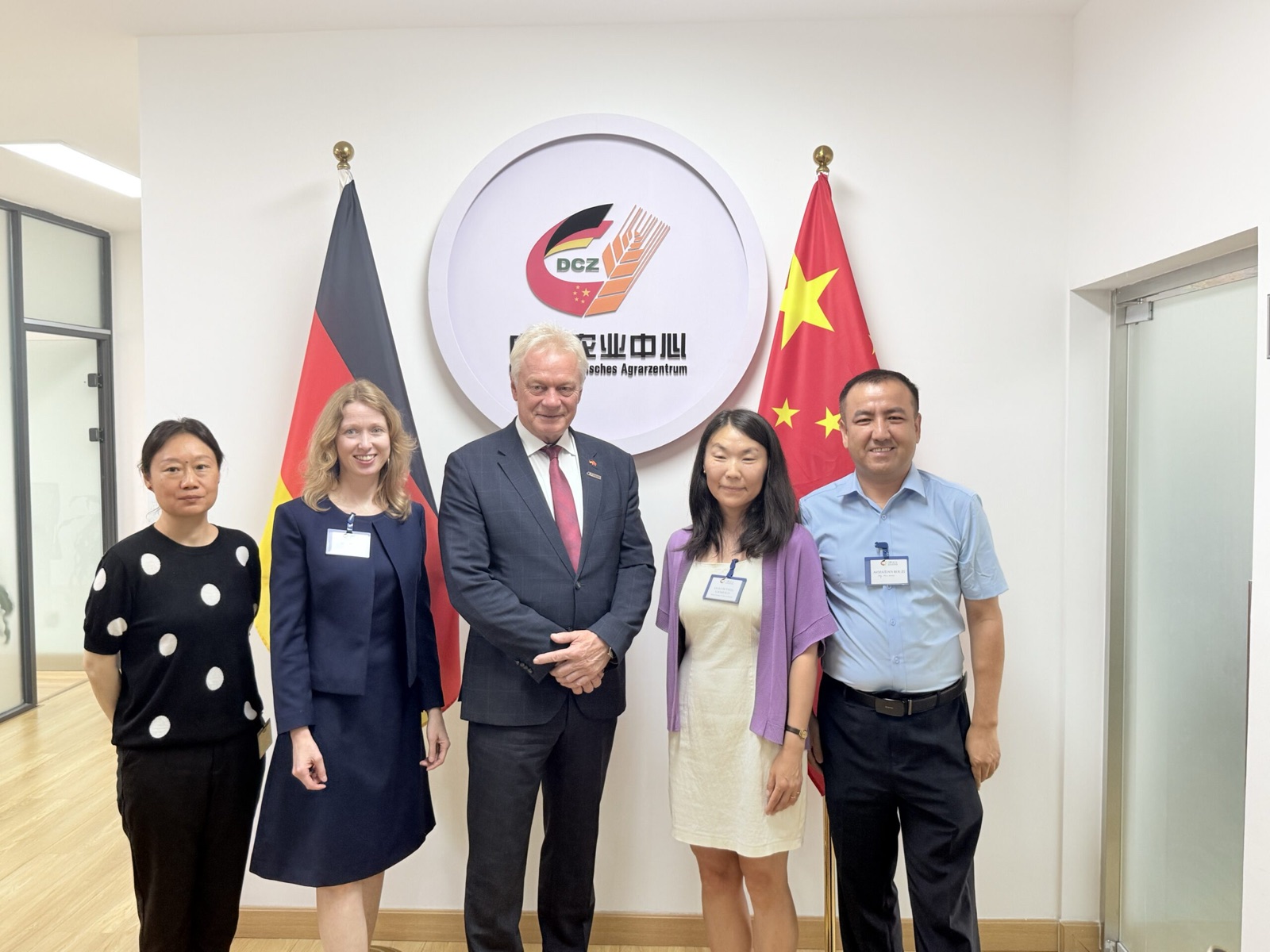Alois Rainer standing with four people in front of German and Chinese flags and the logo of the German-Chinese Agricultural Centre