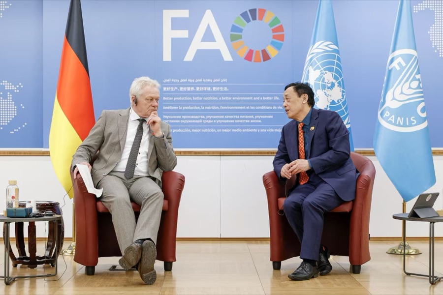 Alois Rainer seated in conversation in front of FAO banners