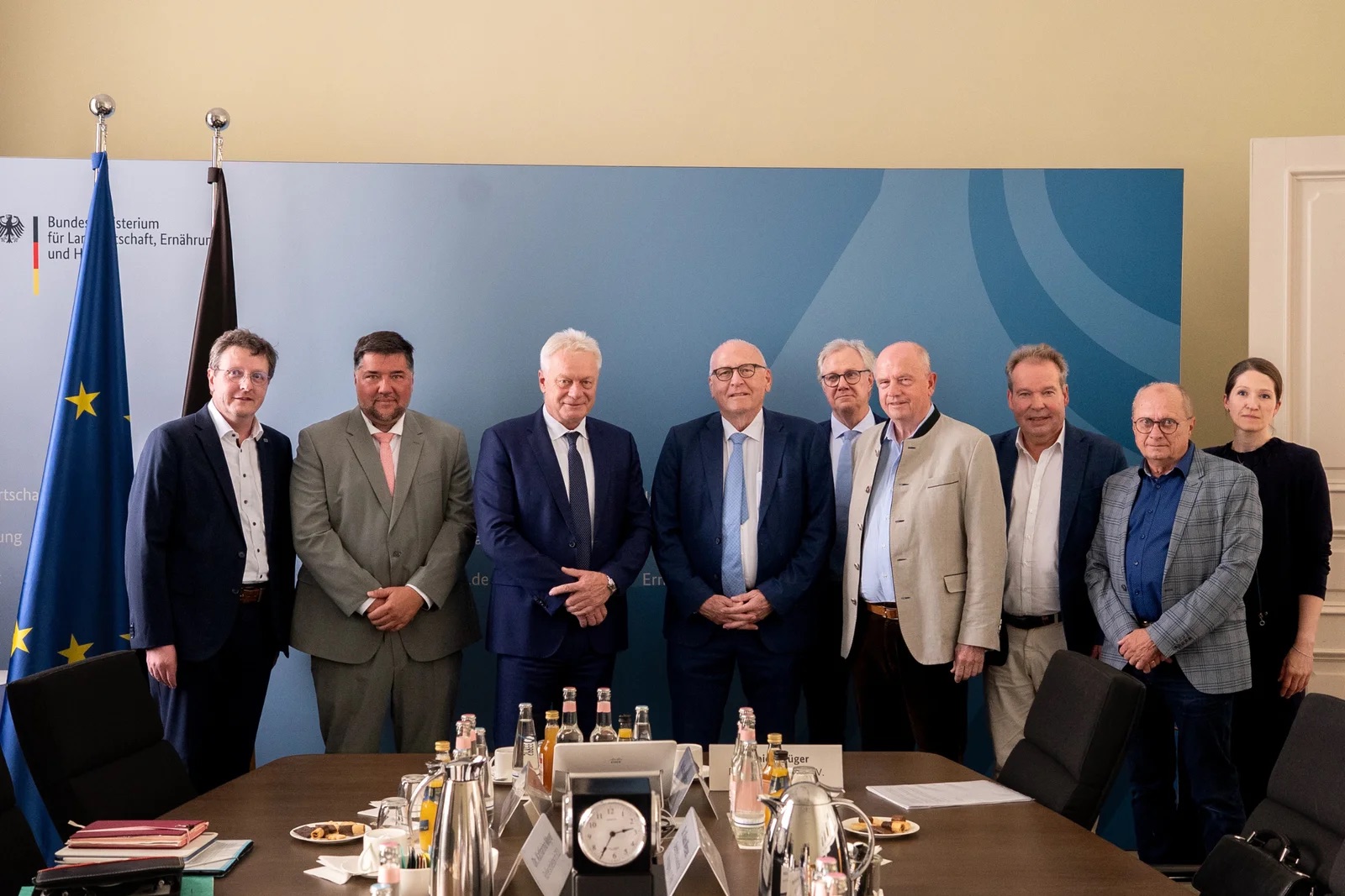 Alois Rainer standing with a group of nine people in a ministry meeting room in front of German and EU flags
